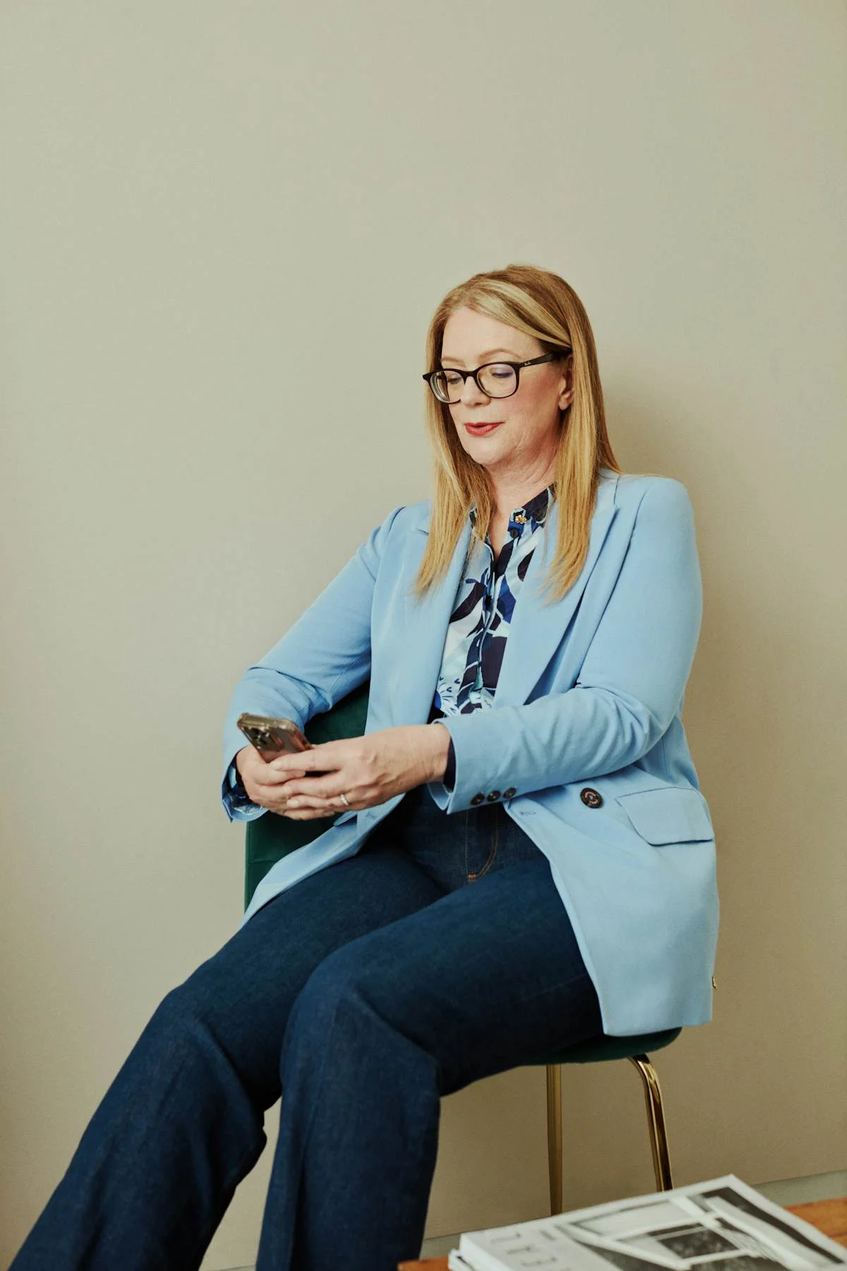 a woman sitting in a chair looking at her cell phone